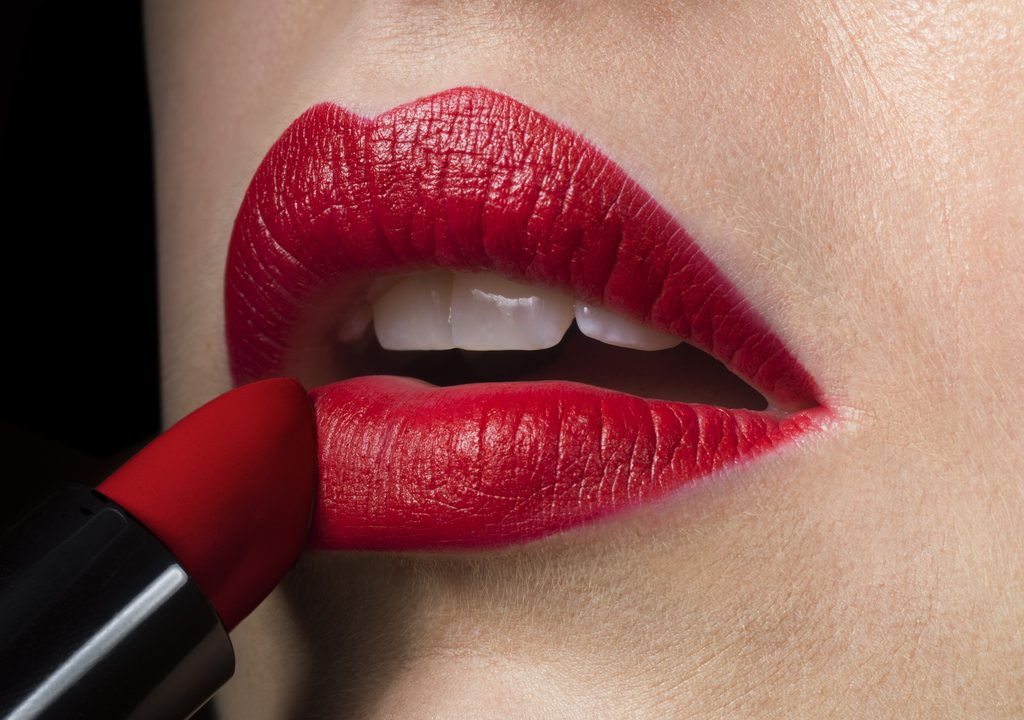 Female applying red lipstick, close up