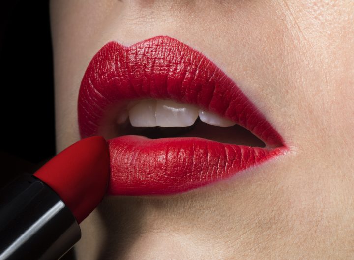 Female applying red lipstick, close up